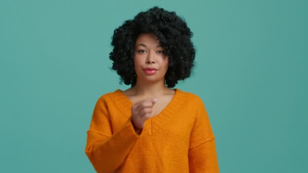 studio zwolnień ruchu strzał wspaniały Afroamerykanka w jasnopomarańczowy sweter patrząc prosto w aparat i pokazuje zamek błyskawiczny, zamykając usta gest wizualizując ciszę, stop nie chcą rozmawiać - Materiał filmowy, wideo