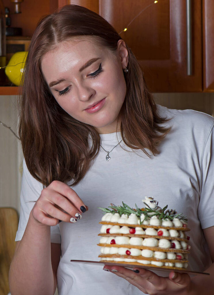 Young blonde girl in her kitchen holding a Christmas cake enjoying the smell - 写真・画像