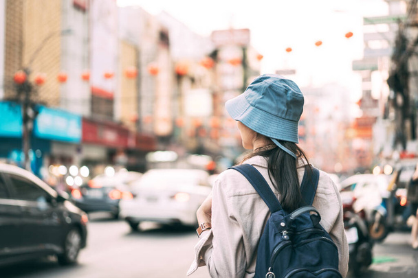Вид сзади идущего молодого человека и рюкзака женщины-путешественника. Люди, путешествующие по городскому образу жизни, посещают рынок уличной еды Бангкок, Таиланд. Концепция летнего путешествия. Боке на заднем плане. - Фото, изображение