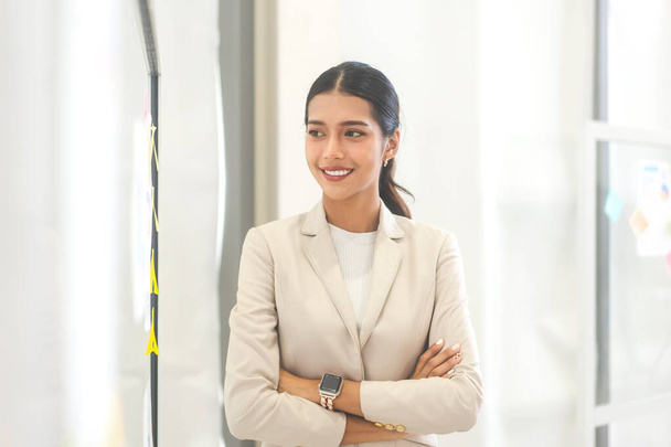 Portrait of young adult southeast business asian entrepreneur woman. Eye looking left side with smile teeth confident wearing white suit in office. - Foto, Imagem