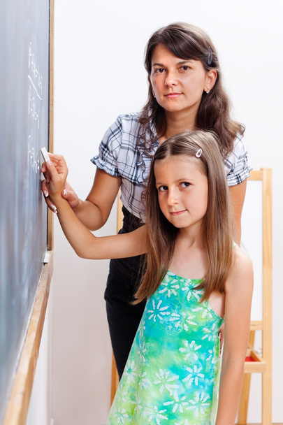 Girl writing on chalkboard with teacher's help - Fotoğraf, Görsel