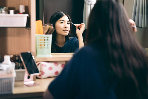 Egyetlen stills wellness boldog életmód készen áll a napi koncepció. Fiatal felnőtt ázsiai nő smink és arc bőrápoló tükör előtt öltözőben otthon. - Fotó, kép