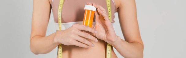 Vitaminli ve şeritli, gri pankartta izole edilmiş sağlıklı kadın görüntüsü - Fotoğraf, Görsel
