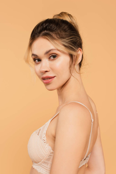 portrait of young woman with natural makeup posing in lace bra isolated on beige - Foto, Imagen