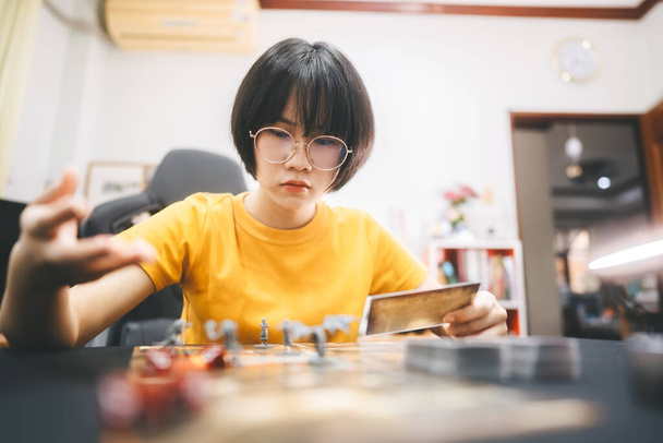 Role Playing Tabletop und Brettspiele Hobby-Konzept. Junge erwachsene asiatische Frau genießt das Geschichtenerzählen. Vordergrund verwischen mit Monsterminiaturen und Würfelkomponente. - Foto, Bild