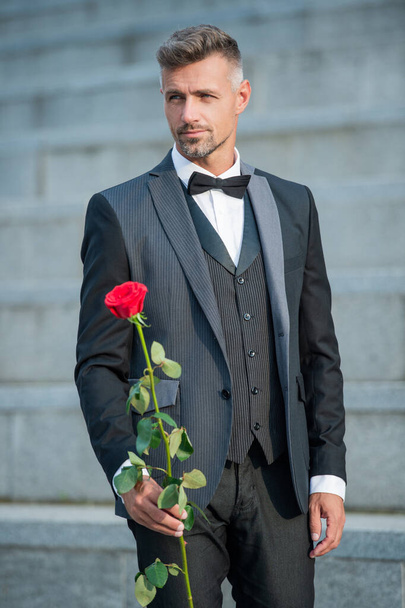 special occasion concept. mature man with rose for special occasion. tuxedo man outdoor at special occasion. - Fotó, kép