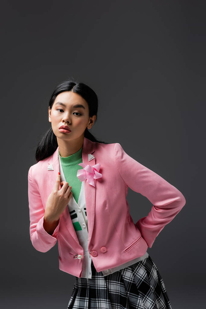 Stylish asian woman in pink jacket posing isolated on grey  - 写真・画像