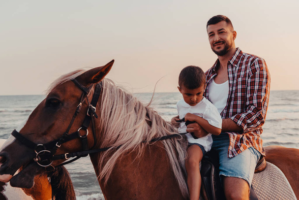 Otec a syn si užívají jízdu na koních u moře. Selektivní soustředění. Kvalitní fotografie - Fotografie, Obrázek