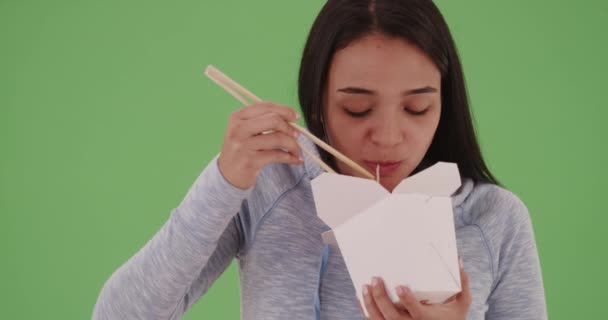 Junges hispanisches Mädchen isst chinesisches Essen auf grünem Bildschirm. Auf einem grünen Bildschirm, der getastet oder zusammengesetzt werden soll. - Filmmaterial, Video