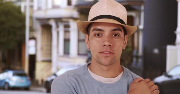 Knappe duizendjarige Latino gemengd ras man staan op straat met hoed. Fashionable jonge Mexicaanse man in de twintig draagt fedora. 4k - Video