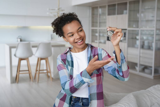 Joyful young african american woman showing house keys at new home. Biracial teen girl homeowner, tenant feels happiness with relocation or purchase of flat. Real estate rent, first own apartment. - Valokuva, kuva