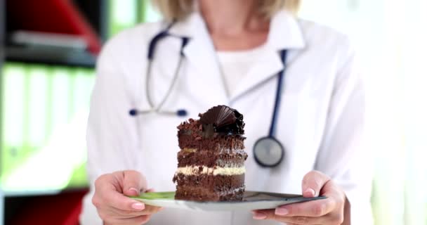 Médico nutricionista sosteniendo pedazo de pastel de chocolate en sus manos primer plano película 4k cámara lenta. Comida chatarra exceso de carbohidratos concepto - Imágenes, Vídeo