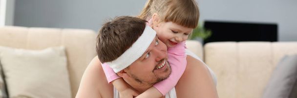 Portrait of father and daughter have fun playing together, physical exercise with kid on back. Child spend time with father. Childhood, parenthood concept - Photo, Image
