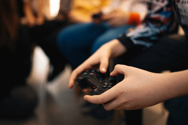 Ruce malého chlapce hrajícího videohry doma s přáteli. Černý gamepad v dětských rukou - Fotografie, Obrázek