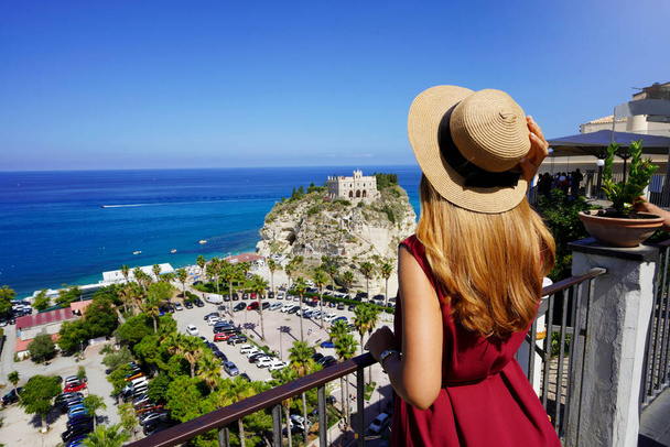 イタリア観光。美しいファッションの女の子の背面ビューは、神々の海岸、カラブリアのトロピー村の景色を楽しんでいます。ヨーロッパでの夏休み. - 写真・画像