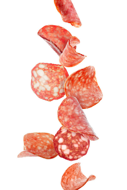 Летающие кусочки вкусной салями, изолированные на белом - Фото, изображение