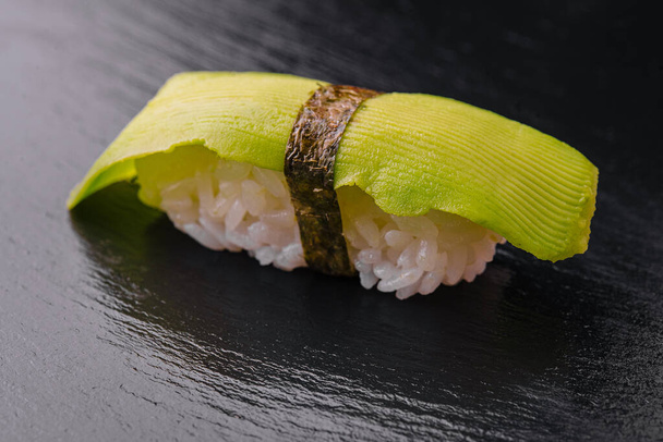 Ιαπωνικό σετ σούσι με αβοκάντο σε μαύρο ξύλο - Φωτογραφία, εικόνα