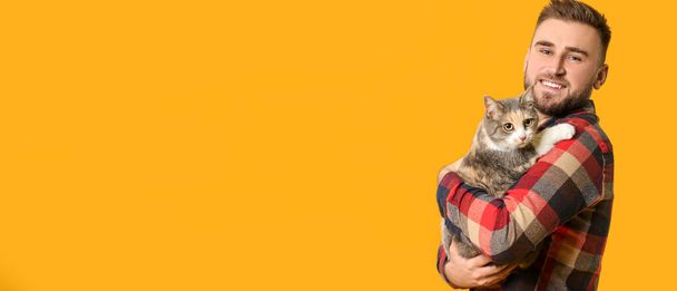 Young man and cute cat on orange background with space for text - Foto, immagini