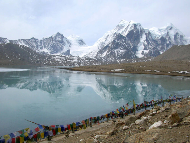 Kiehtova näkymä Mt. Khangchenghao (uros) ja Mt. Chomoyomo (naaras) peilasi Gurudongmar-järvellä, joka sijaitsee 17800 jalan korkeudessa lähellä Intian ja Kiinan rajaa Sikkimissä. Tämä on buddhalainen pyhä paikka ja suosittu matkailukohde Sikkimissä. - Valokuva, kuva