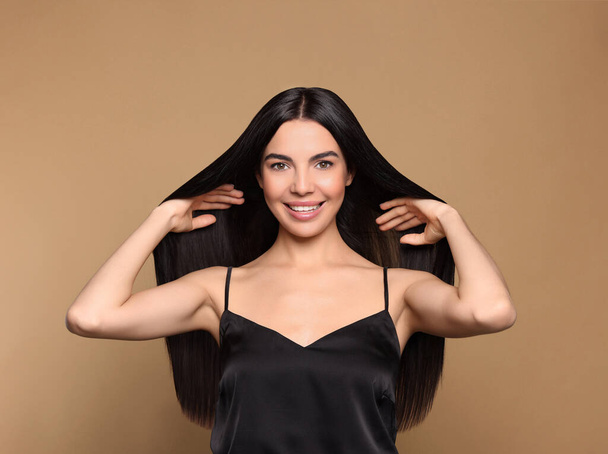 Πορτρέτο της όμορφης νεαρής γυναίκας με υγιή δυνατά μαλλιά σε μπεζ φόντο - Φωτογραφία, εικόνα