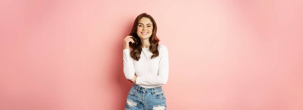 Spring and beauty. Young beautiful and stylish female model posing against pink background, cross arms on chest, smiling happy. - Fotografie, Obrázek
