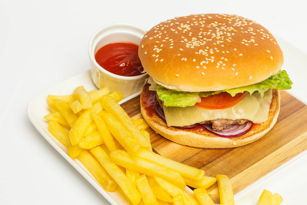 cheeseburger dla smakoszy i frytki na drewnianym stole na białym tle. - Zdjęcie, obraz