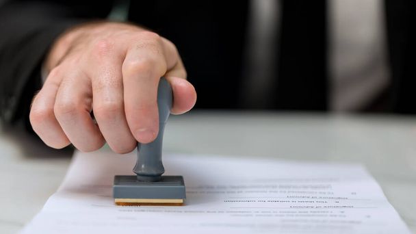 Business Man Stamping With Approved Stamp On Document. Business approve Stamp and certificate concept. Businessman Hands Stamping a document - 写真・画像