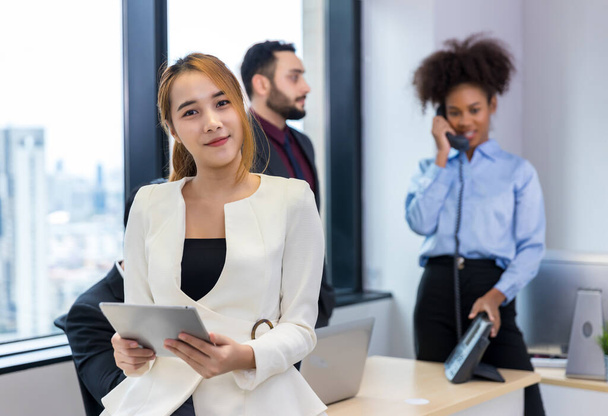 Call center business woman talking on headset. Call center worker accompanied by her team. Customer service executive working at office. - Foto, Imagen