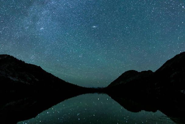 Toxaway Lake, gelegen in Idahos Sawtooth Wilderness gezien op een zomernacht met veel sterren aan de hemel en weerspiegeld in het water oppervlak. - Foto, afbeelding