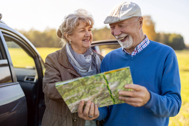 Senior couplelooking en el mapa en un viaje por carretera - Foto, Imagen