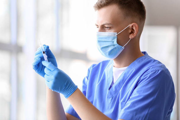 Férfi orvos orvosi maszkban fecskendővel a kórházban - Fotó, kép