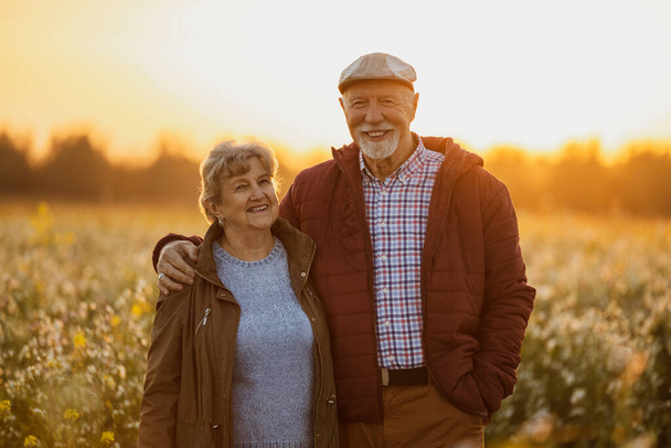 Senior couple in a field in autumn at sunset - Foto, imagen