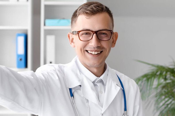Médico varón con anteojos tomando selfie en clínica, primer plano - Foto, Imagen