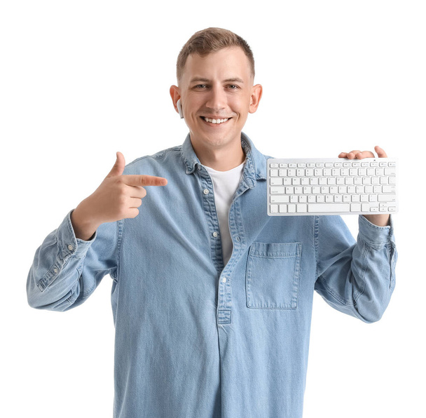 Young man with earphone pointing at computer keyboard on white background - Foto, imagen