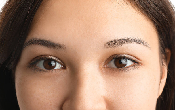 Nuori aasialainen nainen ruskeat silmät valkoisella taustalla, lähikuva - Valokuva, kuva