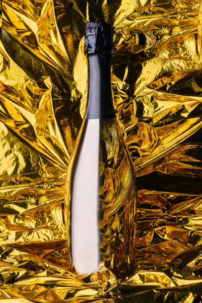 Golden champagne fles op gele achtergrond - Foto, afbeelding