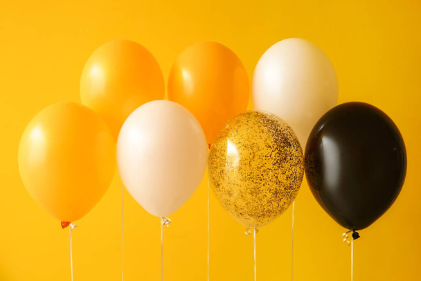 Αποκριάτικα μπαλόνια κοντά κίτρινο τοίχο - Φωτογραφία, εικόνα