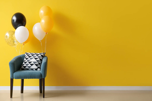 Elegante sillón con globos de Halloween cerca de la pared amarilla - Foto, imagen