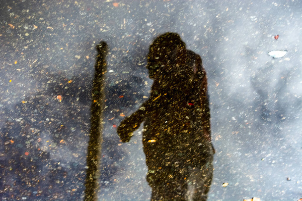 Salvador, Bahia, Brasile - 01 aprile 2018: Riflessione sulla silhouette umana in una pozza d'acqua piovana. Giornata nuvolosa. Salvador, Bahia, Brasile. - Foto, immagini