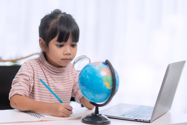 Азиатская маленькая девочка изучает модель земного шара, концепцию спасения мира и учится через игровую деятельность для обучения детей дома. - Фото, изображение