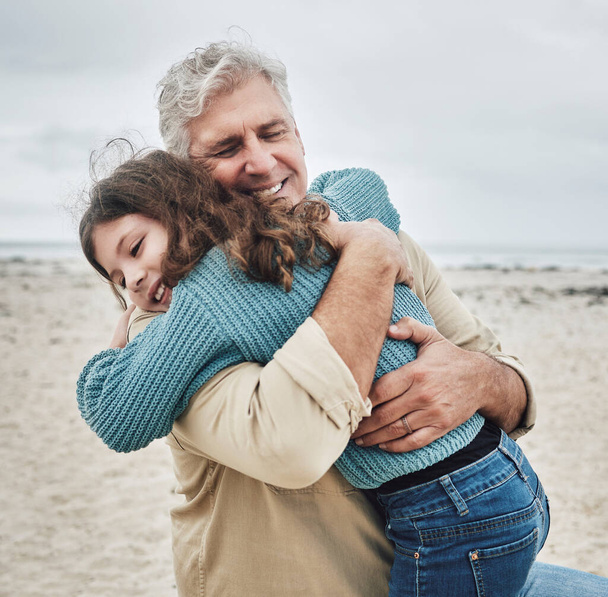 Glücklich umarmen sich Großvater und Kind am Strand für Liebe, Fürsorge und familiäre Bindung im Freien. Opa umarmt Enkelkind und umarmt Beziehung in freudigem Glück für gemeinsame Freizeit in der Natur. - Foto, Bild