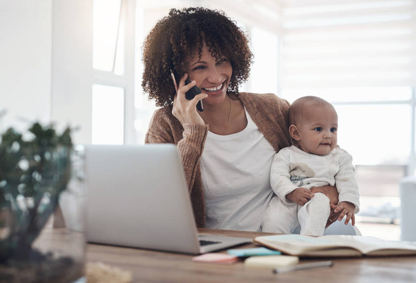 Az idő és a figyelem megosztása a munka és a baba között. egy fiatal nő okostelefont és laptopot használ, miközben az imádnivaló kislányáról gondoskodik otthon. - Fotó, kép