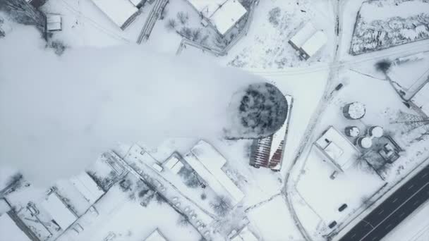 Flug über ein Industriegebiet mit einer Laderampe mit Lastkähnen und Wasserhähnen aus gefrorenem Eis. Rauchschwaden, Dampf aus der Produktion im Hintergrund der Stadt. Hochwertiges FullHD-Filmmaterial - Filmmaterial, Video