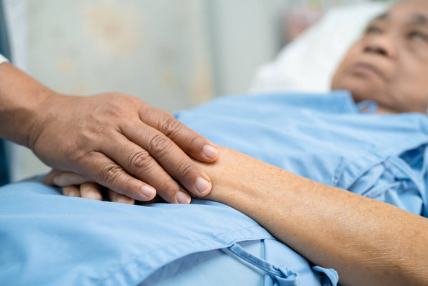 Arzt hält berührende Hände asiatische Seniorin oder ältere Dame Patientin mit Liebe, Fürsorge, Hilfe, Ermutigung und Empathie auf Krankenstation, gesundes starkes medizinisches Konzept - Foto, Bild
