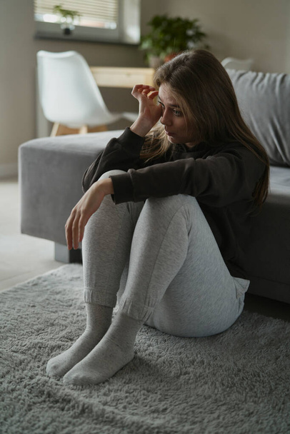 Blanke vrouw zit aan de vloer en huilt thuis - Foto, afbeelding
