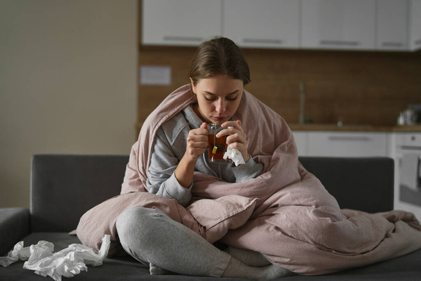 Blanke vrouw bedekt onder het dekbed met thee thuis - Foto, afbeelding