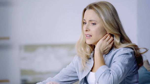 displeased woman looking away and suffering from pain in neck at home  - Foto, Imagem
