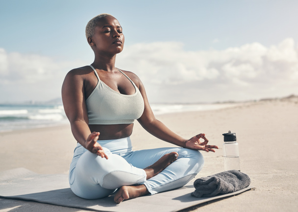 Una mentalidad fuerte puede cambiar la forma en que procesas las emociones. una mujer meditando durante su rutina de yoga en la playa - Foto, imagen