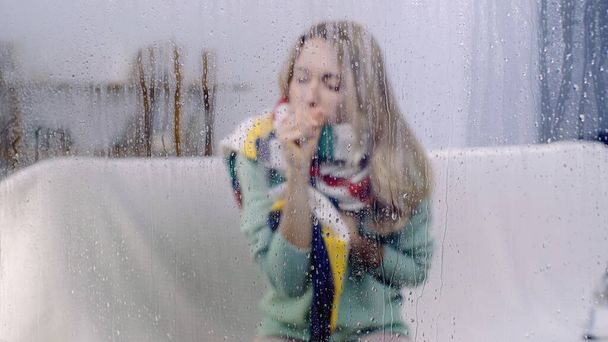 mujer enferma tosiendo detrás de una ventana mojada con gotas de lluvia  - Foto, imagen