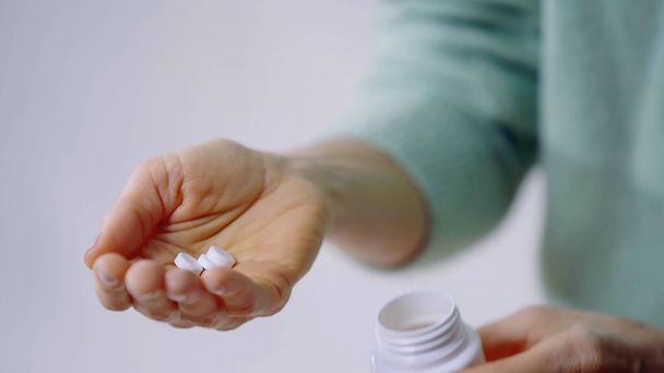 μερική άποψη της γυναίκας που κατέχουν χάπια και μπουκάλι στα χέρια - Φωτογραφία, εικόνα